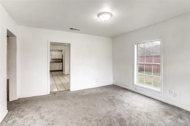 an empty room with a window and a kitchen