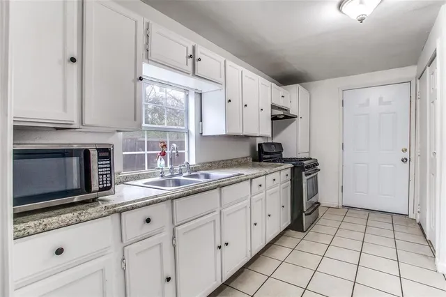 a kitchen with kitchen island granite countertop white cabinets stainless steel appliances a sink and a window