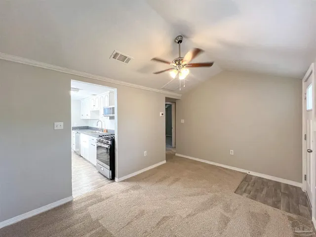 an empty room with a chandelier fan and a bathroom