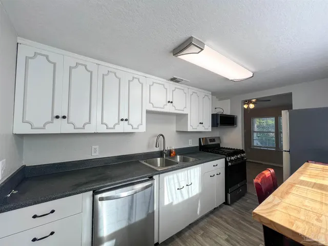 a kitchen with granite countertop a sink a stove and cabinets