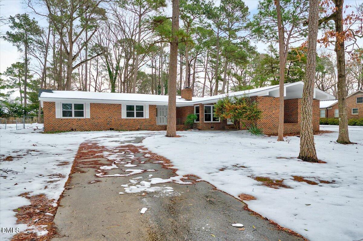 a view of a blue house with snow on the road