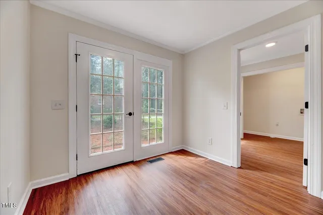 an empty room with wooden floor and windows
