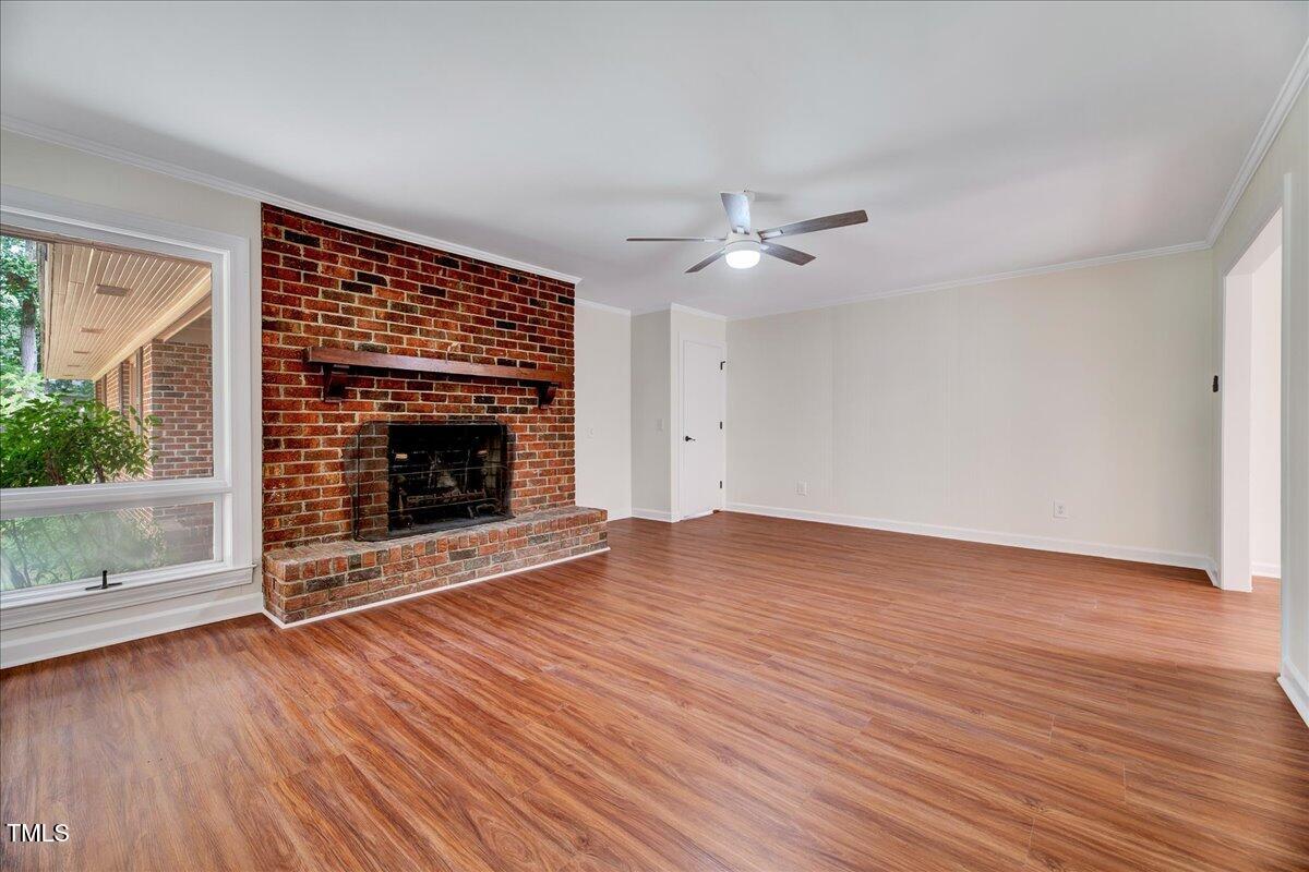 2585 Cabin Branch Road Kinston, NC 28504 - Photo 26 of 42 an empty room with wooden floor fireplace cabinet and windows