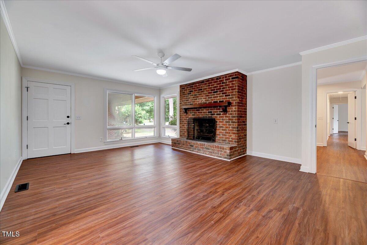 2585 Cabin Branch Road Kinston, NC 28504 - Photo 8 of 42 an empty room with wooden floor fireplace and windows