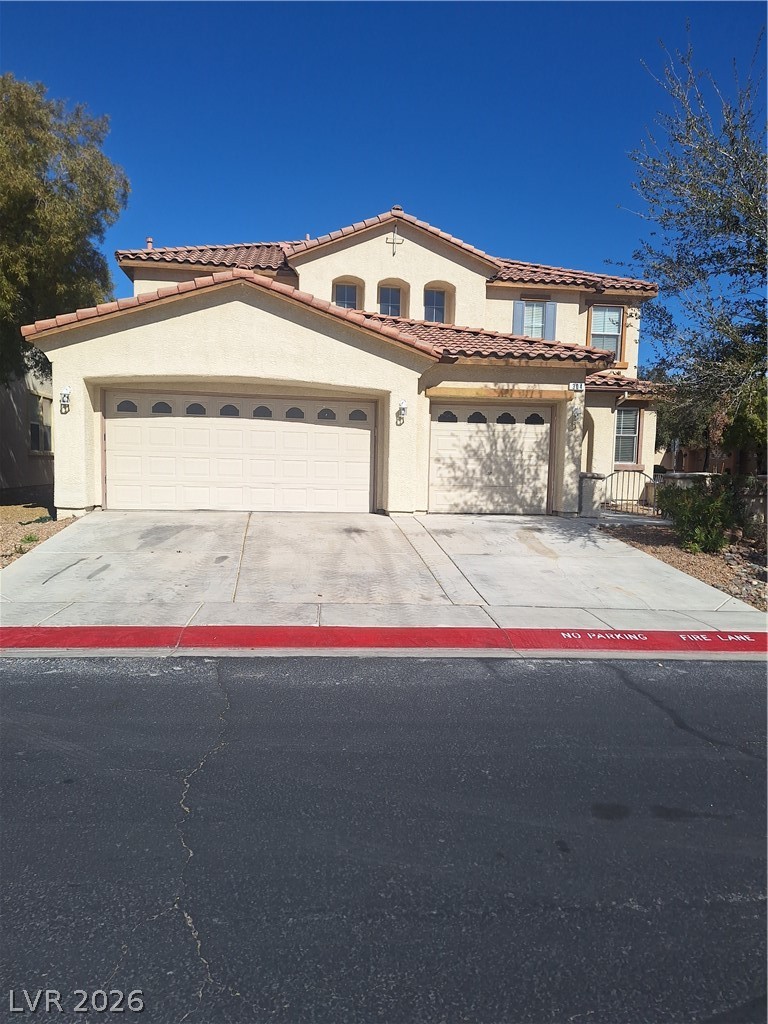 Mediterranean / spanish home with stucco siding, concrete driveway, and a tiled roof