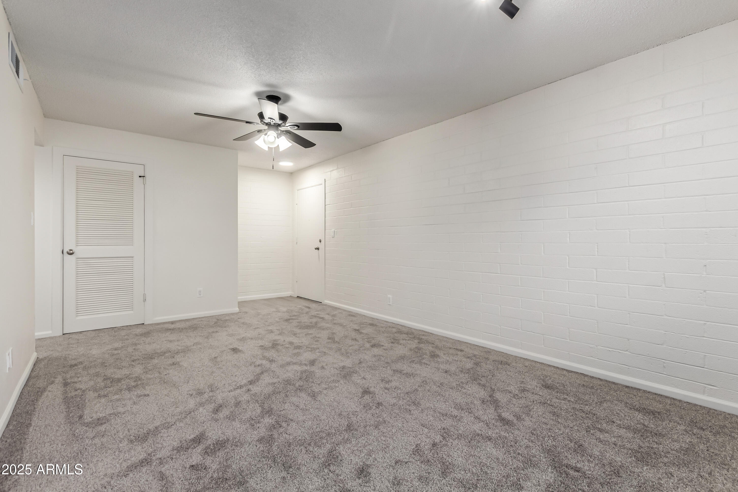 2608 West Berridge Lane, Unit C220 Phoenix, AZ 85017 - Photo 5 of 21 an empty room with chandelier fan and windows