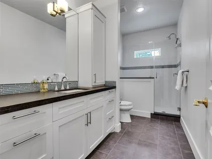 a bathroom with a sink a toilet a mirror and shower