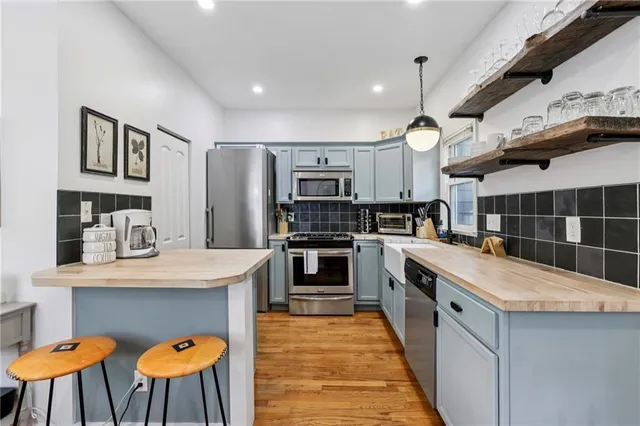 a kitchen with stainless steel appliances kitchen island granite countertop a table chairs in it and wooden floors