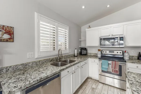 a kitchen with granite countertop a sink a stove and cabinets
