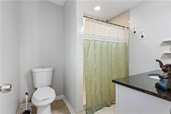a bathroom with a granite countertop toilet and a sink
