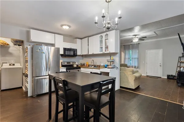a kitchen with stainless steel appliances a table chairs refrigerator and cabinets