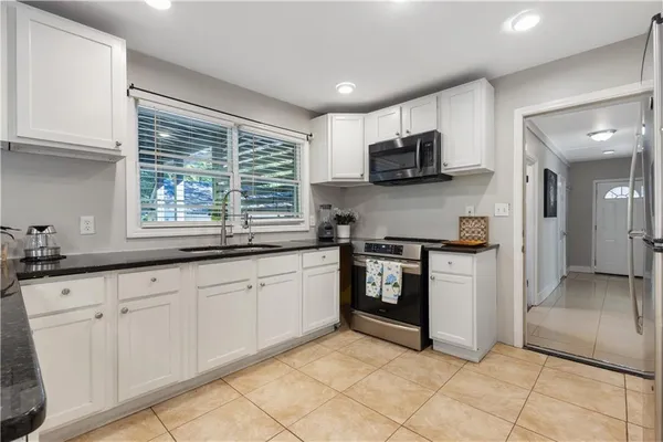 a kitchen with granite countertop white cabinets and stainless steel appliances