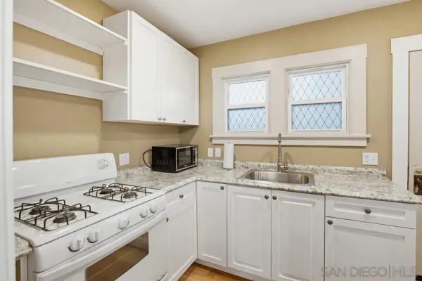 a kitchen with granite countertop a sink a stove a microwave and cabinets