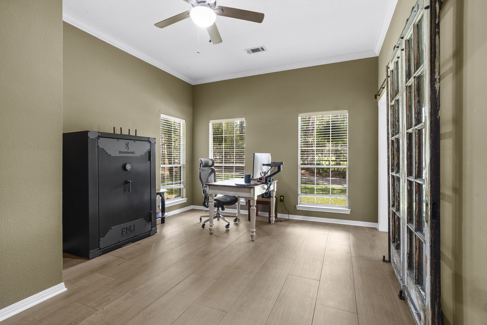 19610 Timber Ridge Drive Magnolia, TX 77355 - Photo 21 of 50 This bright and functional home office features large windows, a ceiling fan for comfort, a stylish glass-paneled sliding door, and durable porcelain flooring that creates a clean and inviting workspace.