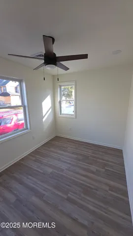 a view of an empty room with wooden floor and window