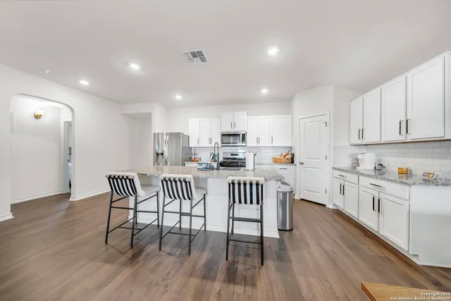 a kitchen with white cabinets and chairs