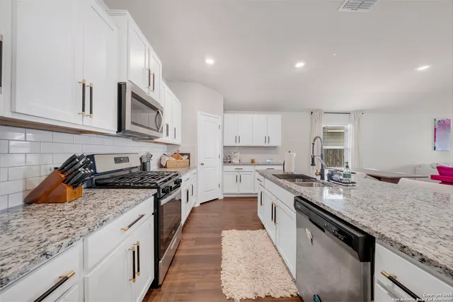 a kitchen with granite countertop sink stove and cabinets