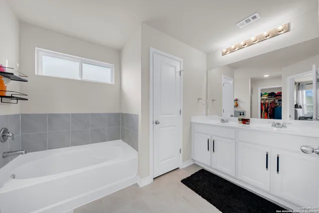 a bathroom with a tub a sink and a mirror