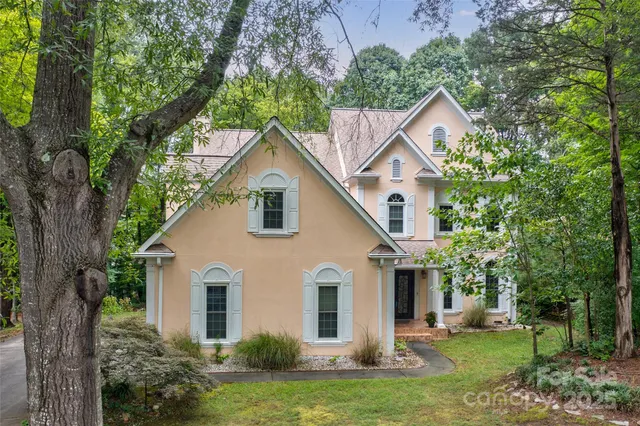 a view of a yard in front of a house with plants and large tree