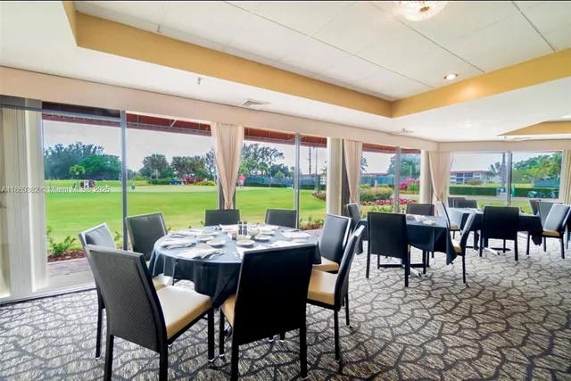 a room with lots of tables a large window and chairs