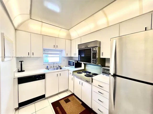 a kitchen with stainless steel appliances a refrigerator sink stove and white cabinets