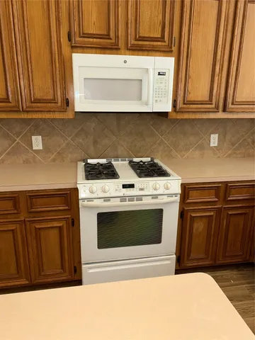 a kitchen with stainless steel appliances granite countertop a stove a microwave oven and a sink with cabinets