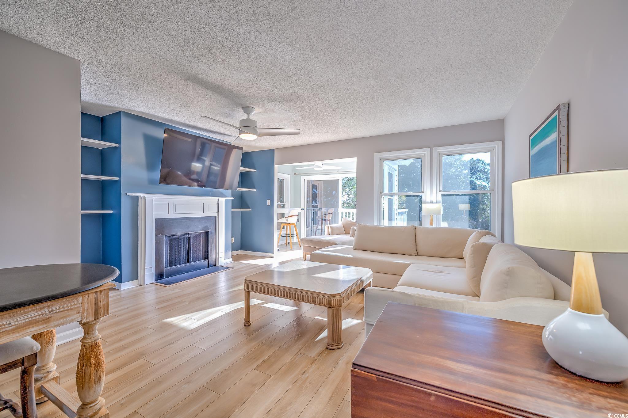 4999 Highway 17 Business, Unit 305 Murrells Inlet, SC 29576 - Photo 14 of 27 Living area with a textured ceiling, built in features, wood finished floors, a fireplace with flush hearth, and ceiling fan