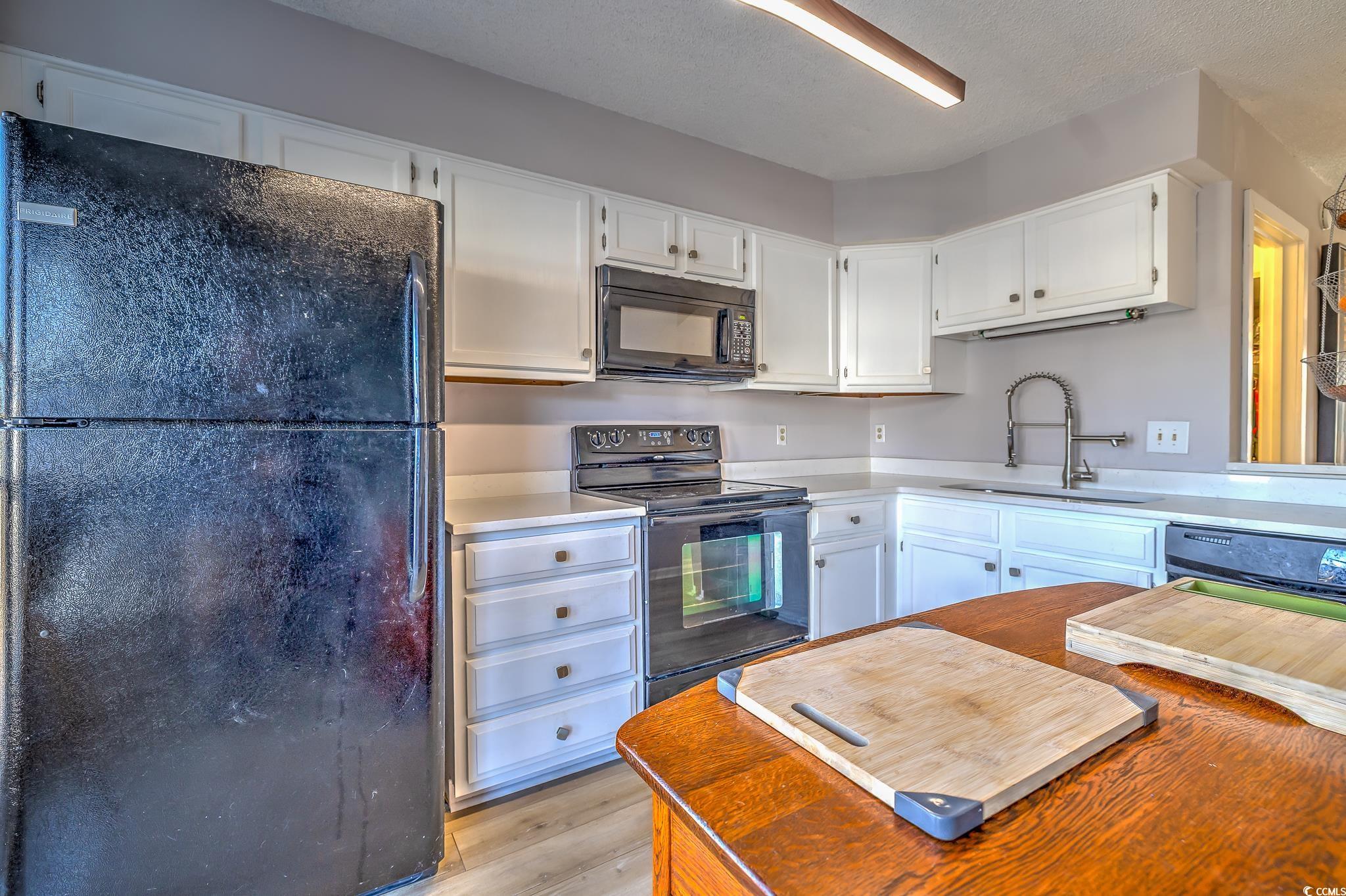 4999 Highway 17 Business, Unit 305 Murrells Inlet, SC 29576 - Photo 9 of 27 Kitchen featuring black appliances, white cabinetry, butcher block countertops, and light wood finished floors