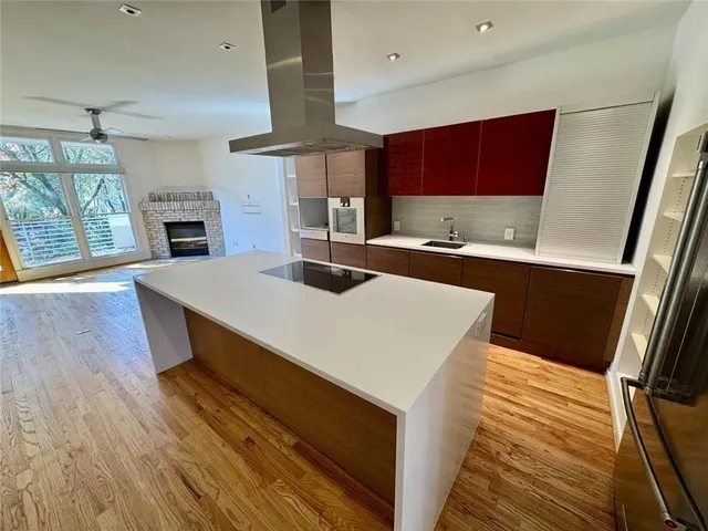 a large kitchen with stainless steel appliances a large counter top a stove and a wooden floors