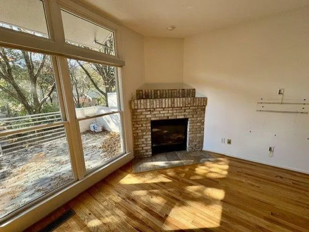 a view of empty room with wooden floor and fireplace