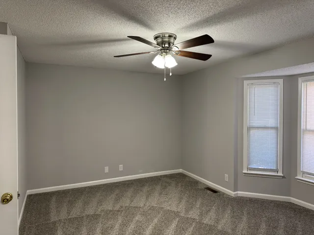 an empty room with windows and fan