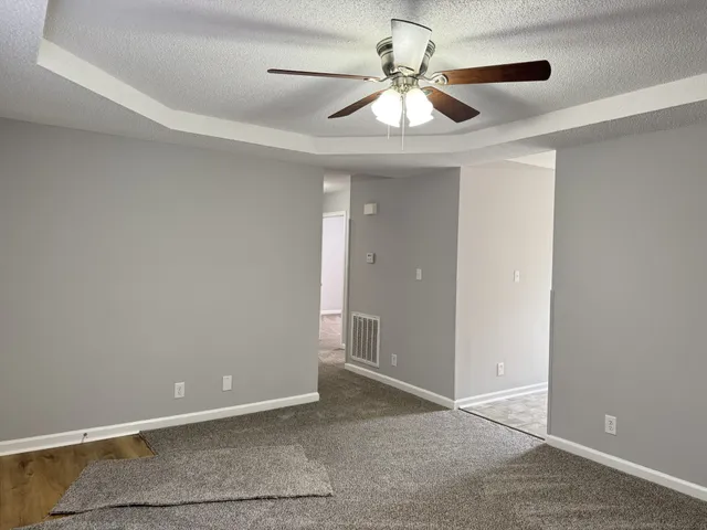an empty room with chandelier fan and windows