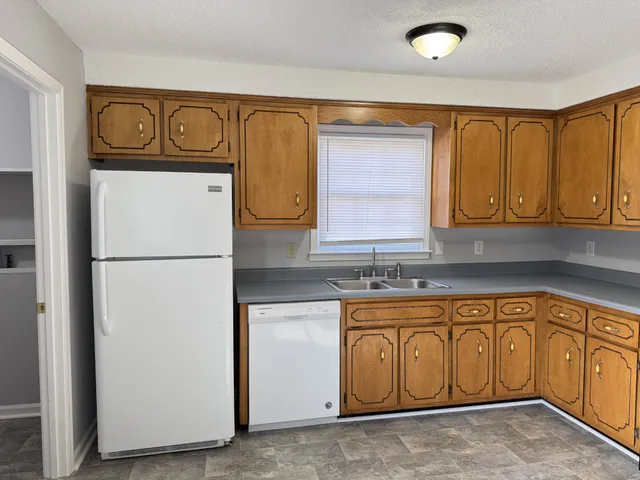 a kitchen with stainless steel appliances granite countertop a refrigerator a stove and a sink with wooden cabinets