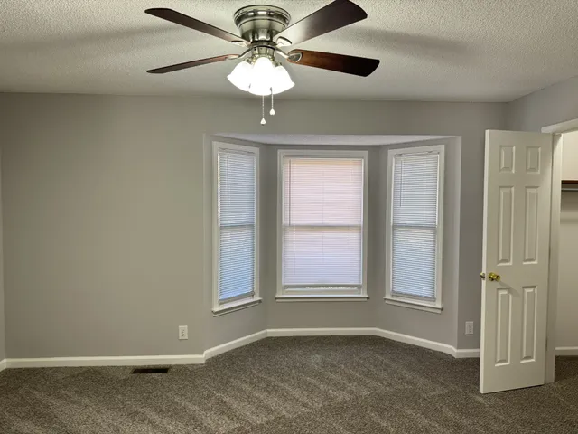 an empty room with windows and fan