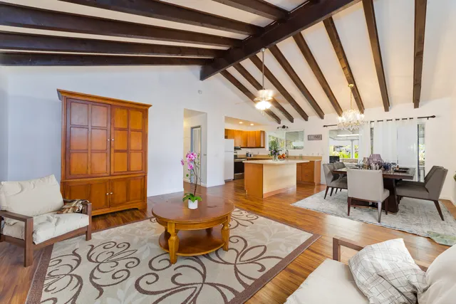 a living room with stainless steel appliances kitchen island granite countertop furniture and a wooden floor