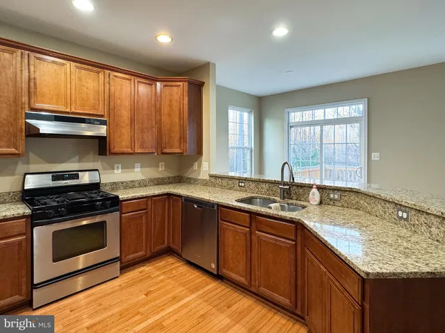 a kitchen with stainless steel appliances granite countertop wooden cabinets a stove a sink and a window