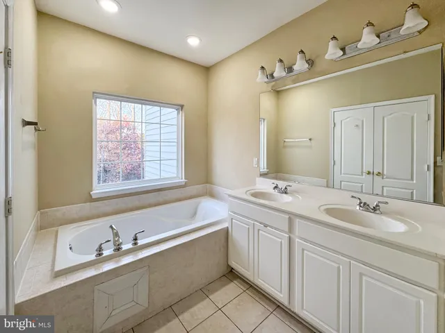 a bathroom with a double vanity sink mirror and bathtub
