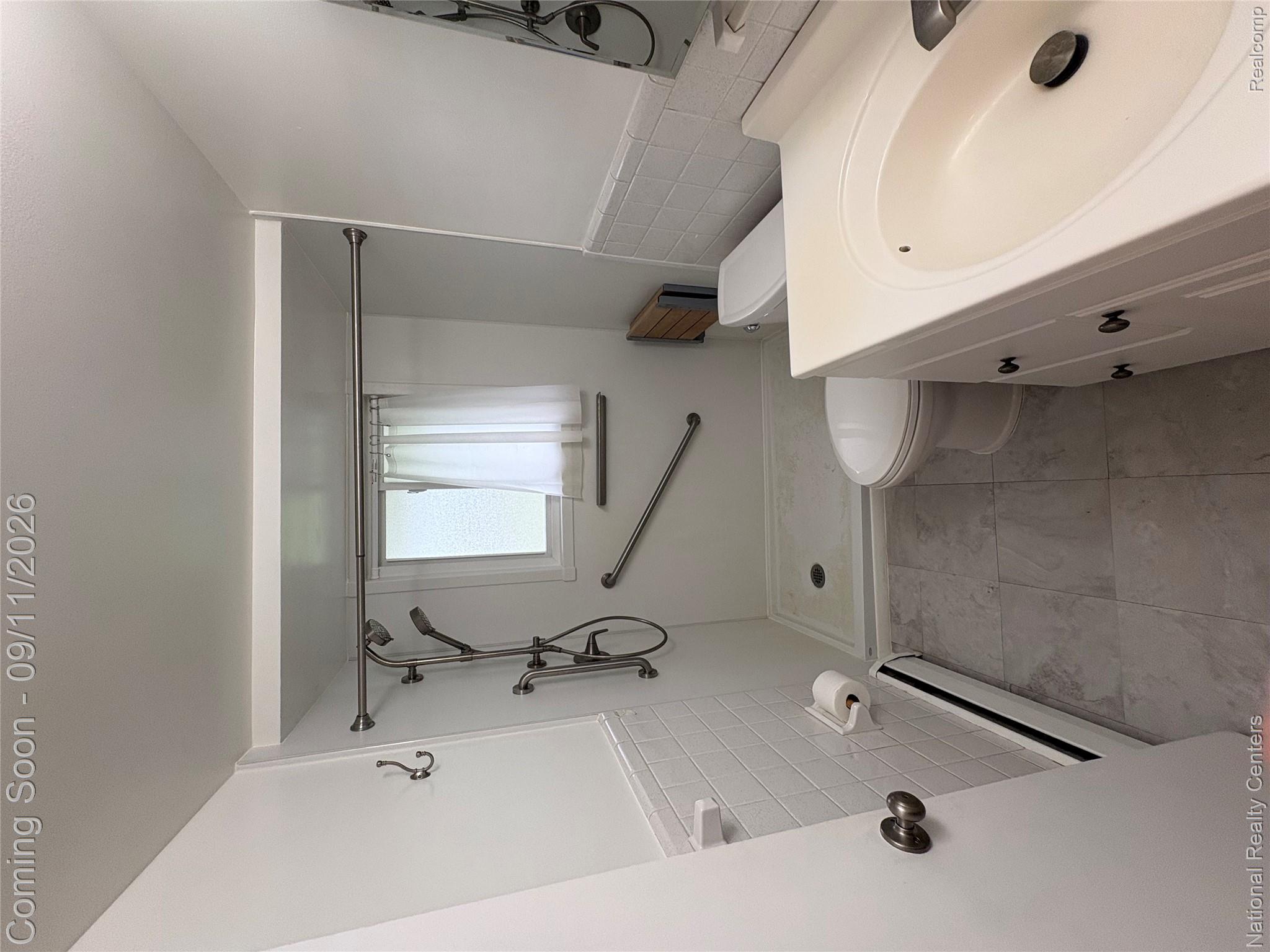 26945 Milford Road, Unit 3 New Hudson, MI 48165 - Photo 17 of 27 Bathroom featuring white subway tile wainscoting, a walk-in shower with grab bars, a single vanity with storage, and grey tile flooring