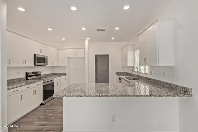 a kitchen with white cabinets appliances a sink and a window