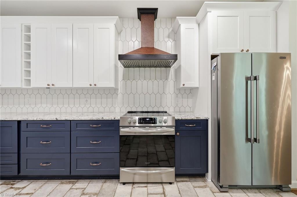 8861 Boylston Road Colfax, NC 27235 - Photo 14 of 50 A custom copper range hood creates a stunning focal point, complemented by custom cabinetry, upgraded countertops, full-height designer tile, and premium stainless steel appliances.