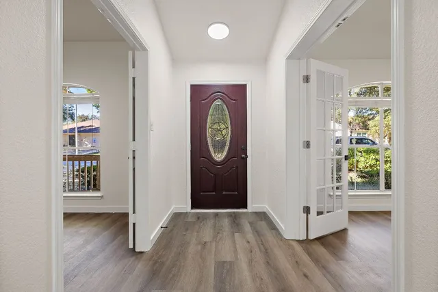 an empty room with wooden floor fireplace and windows