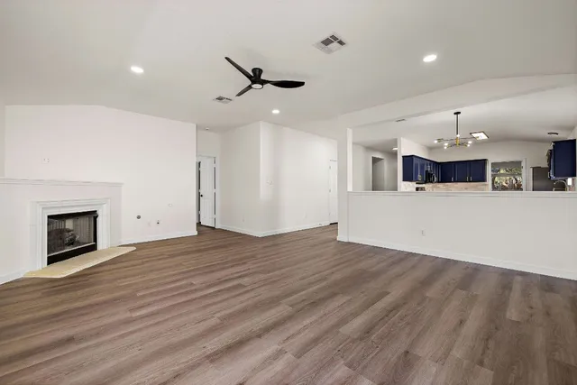 a view of an empty room with a window and wooden floor