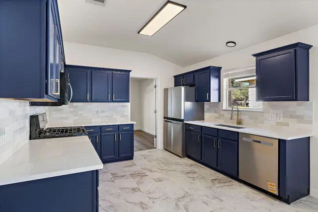 a kitchen with stainless steel appliances granite countertop a sink stove microwave and refrigerator