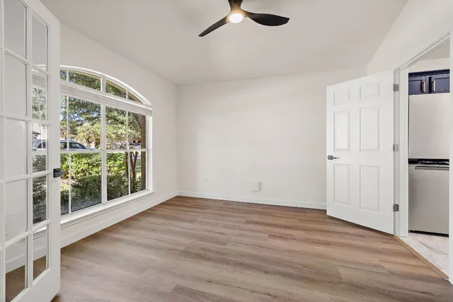 a view of an empty room with a window and wooden floor