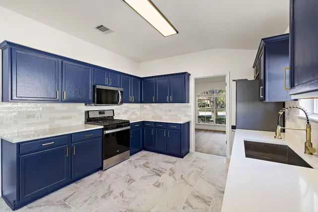 a kitchen with stainless steel appliances granite countertop a stove microwave and sink