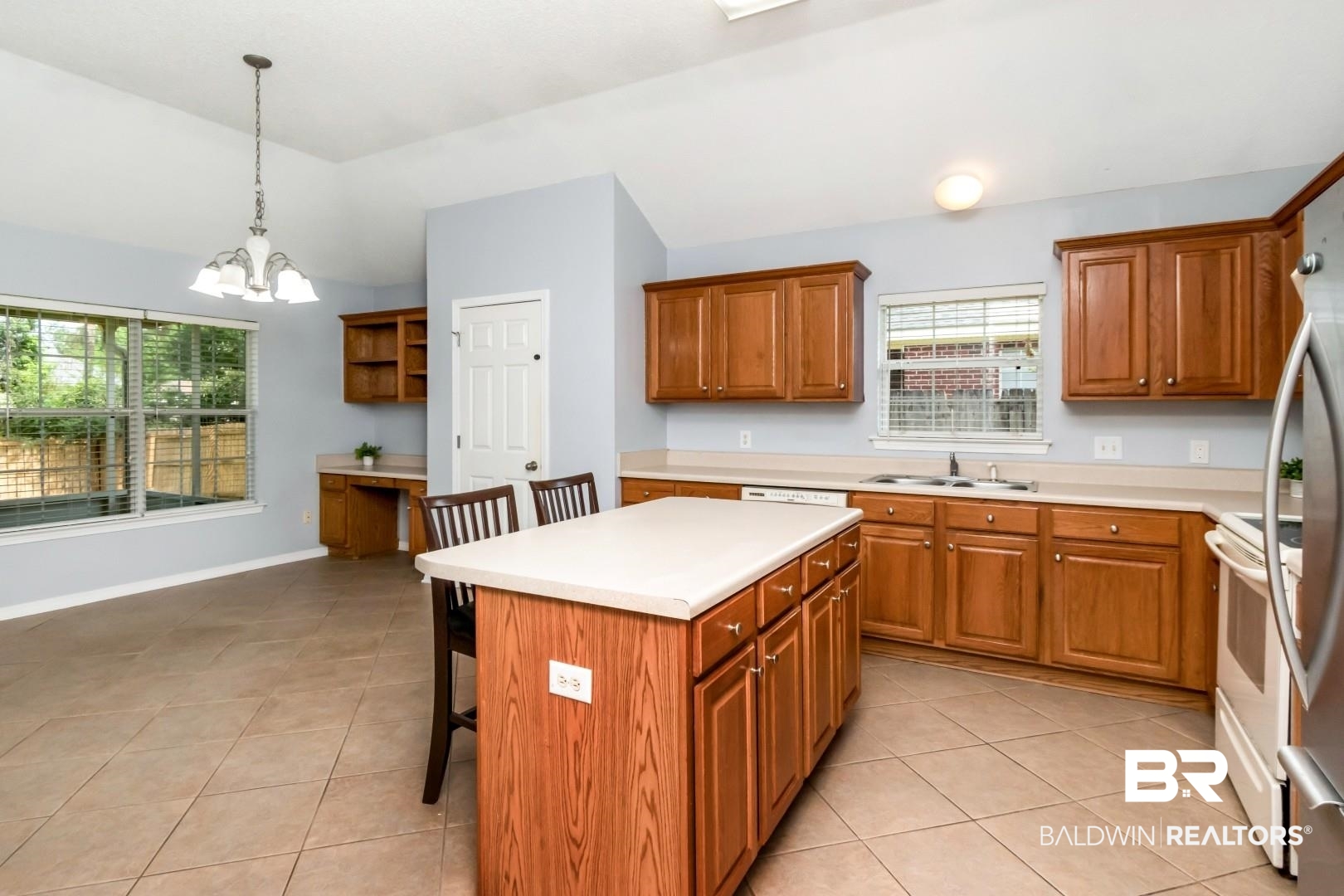 2136 Spring Grove Court Mobile, AL 36695 - Photo 16 of 38 Spacious kitchen featuring a central island with integrated storage, wood-finish cabinetry, light-toned countertops, and tile flooring
