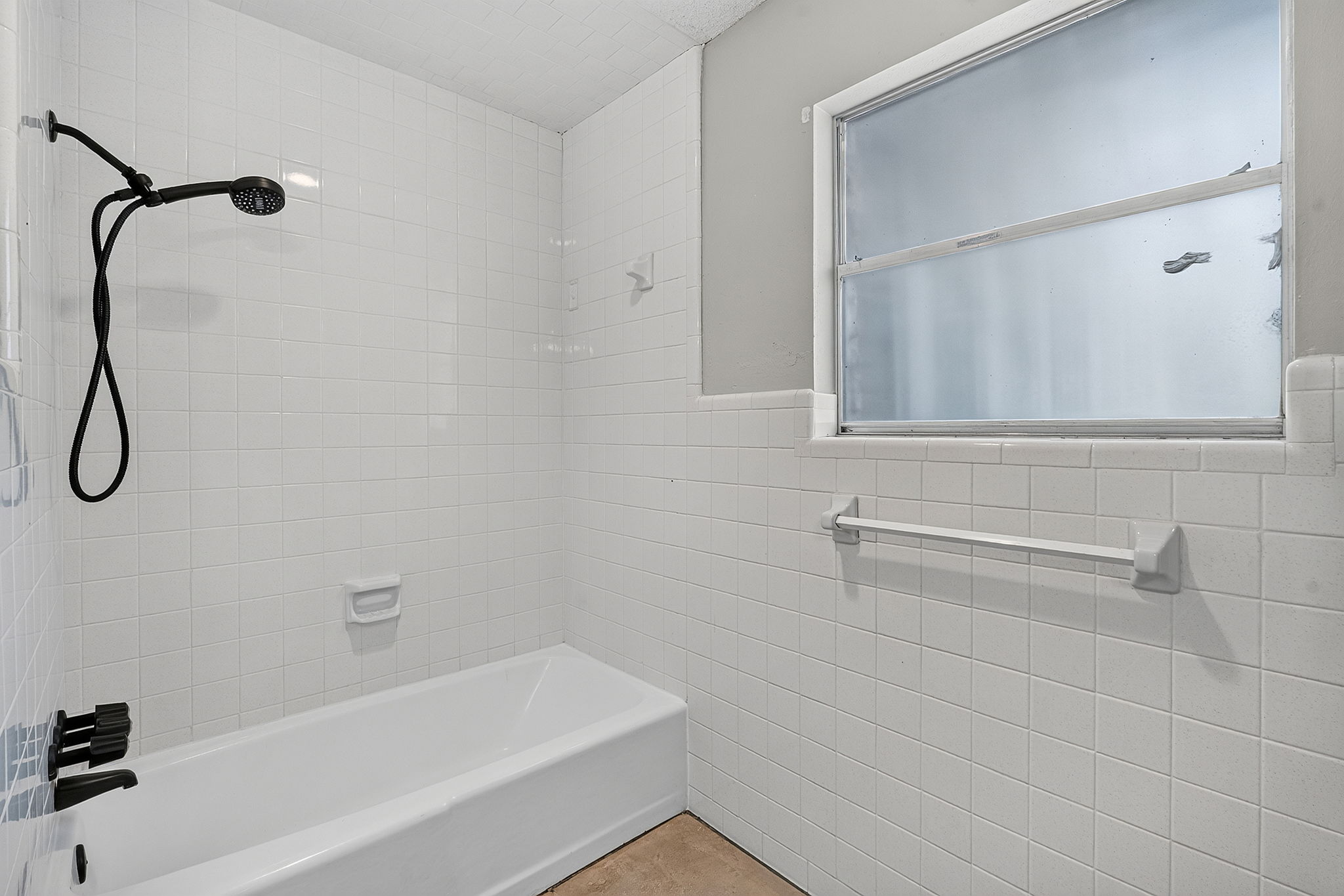 3809 Wyldwood Road Austin, TX 78739 - Photo 20 of 40 Classic white wall tiling surrounds a combined soaking tub and shower setup with overhead window.