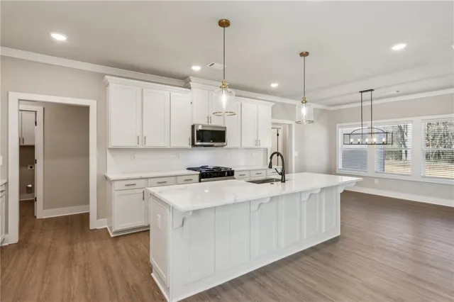 a kitchen with stainless steel appliances granite countertop a sink a stove a refrigerator and island with wooden floor