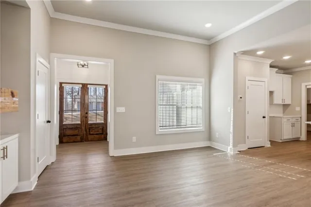 a view of an empty room with wooden floor and a window