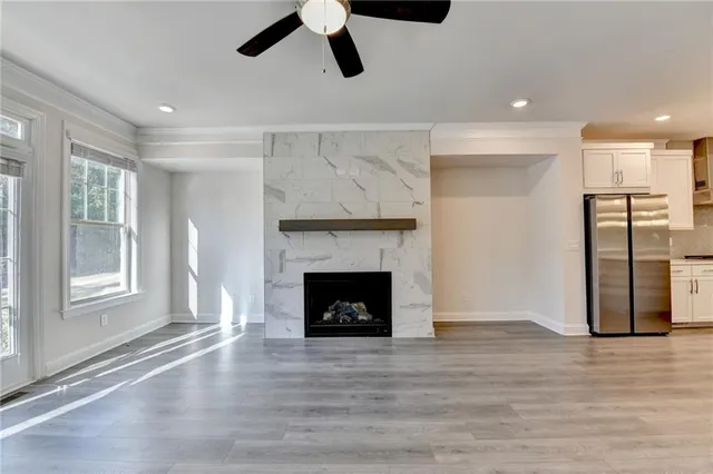 a view of an empty room with wooden floor fireplace and a window
